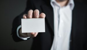 Person in suit holds a blank business card